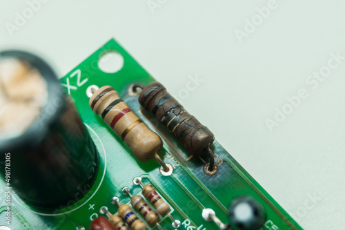 A burned-out resistor on an electronic circuit board. A high-temperature damaged part of an electronic device. Electronics repair. Selective focus photo