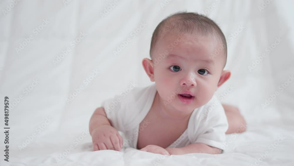 Happy family, Cute Asian newborn baby boy lying play on white bed look at camera with laughing smile happy face. Little innocent new infant adorable child in first day of life. Mother's Day concept. Happy family, Cute Asian newborn baby boy lying play on white bed look at camera with laughing smile happy face. Little innocent new infant adorable child in first day of life. Mother's Day concept.