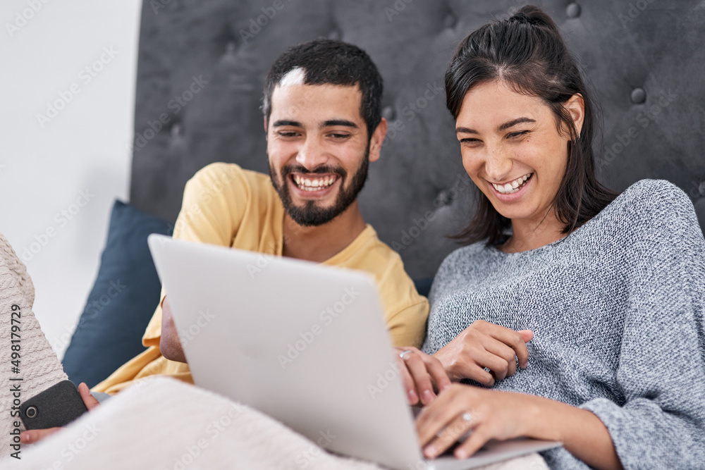 Date night without having to leave the bed. Shot of a young couple using a laptop together in bed.