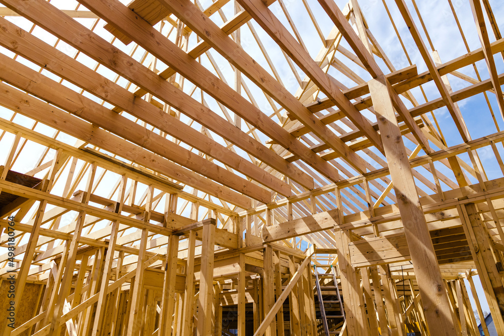 Framing beams of new home under construction wooden roof trusses Framing beams of new home under construction wooden roof trusses