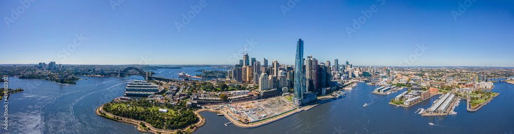 Naklejka premium Panoramic wide aerial drone view of Sydney City spanning from North Sydney to Pyrmont showing the Sydney Harbour Bridge and Sydney Harbour on a sunny day 