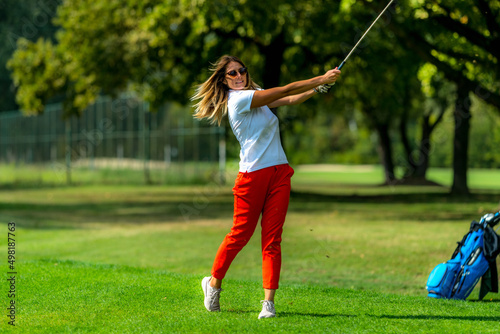 Woman playing golf. Young female golfer on the tee box © Microgen