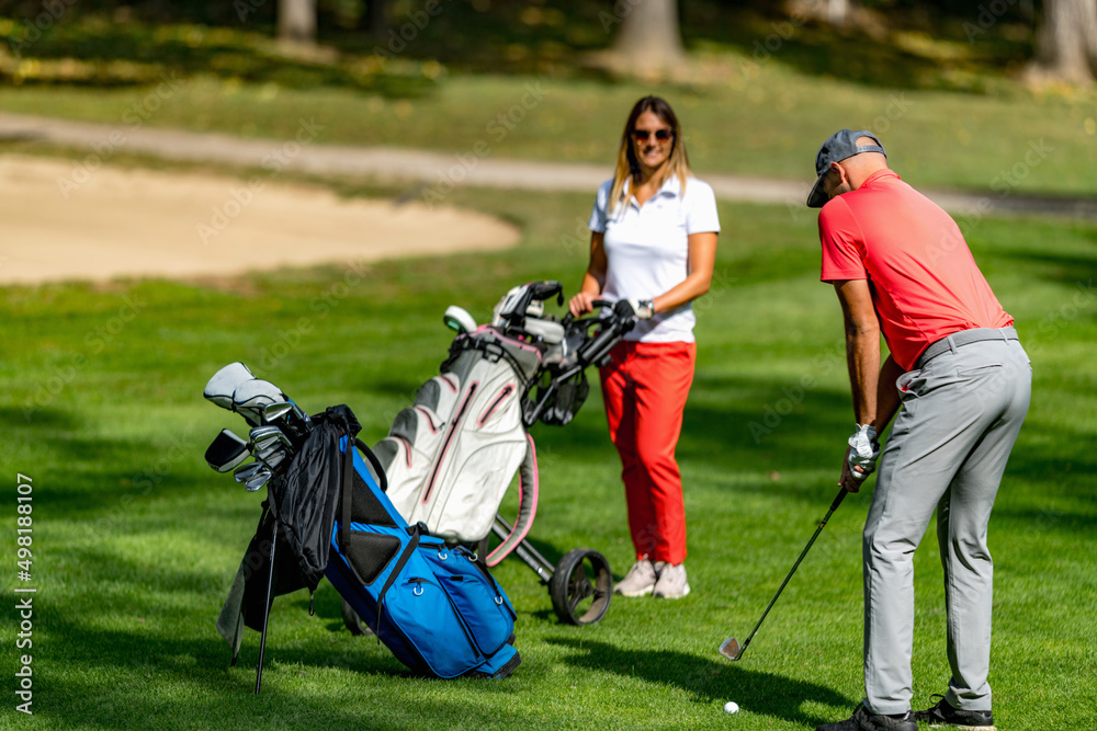 Young couple playing golf on a beautiful summer day Young couple playing golf on a beautiful summer day