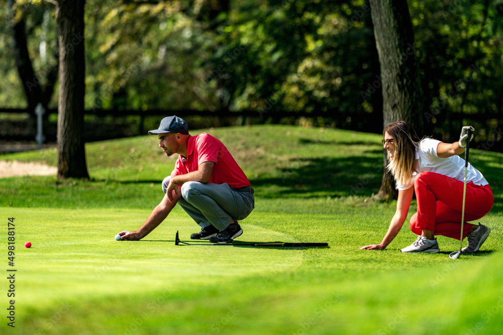 Obraz premium Young couple on a golf course, reading green