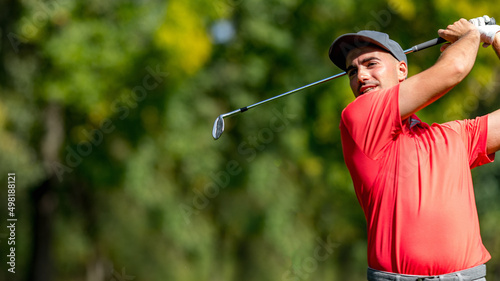 Young golfer in a red shirt playing golf, hitting a ball, convenient copy space