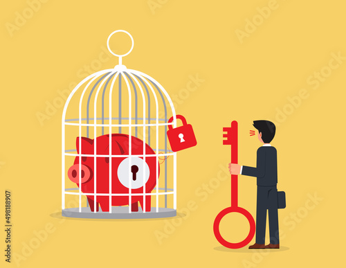 Piggy Bank in large birdcage. businessman holding a key looking at a piggy bank in a cage