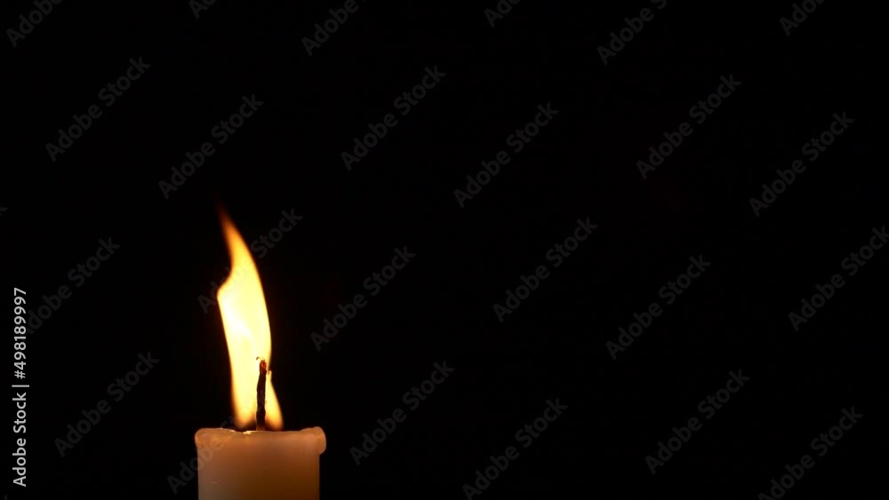 Slow motion closeup burning single candle flame isolated on black background Slow motion closeup burning single candle flame isolated on black background