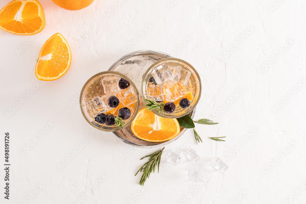 top view of two glasses with fruit water from orange, blueberries, ice cubes. summer cold drink. quenching thirst in the heat. top view of two glasses with fruit water from orange, blueberries, ice cubes. summer cold drink. quenching thirst in the heat.