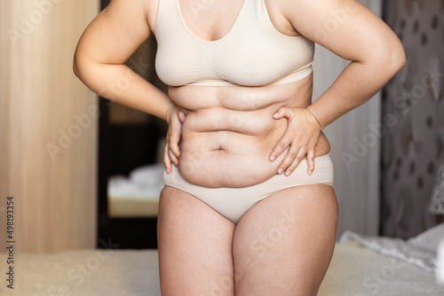 Fotografie Cropped of overweight fat woman holding tummy flabs with obesity, excess fat in underwear