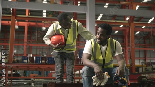 Fotografie Tired worker man sit in warehouses worried taking break with friend from hard wo