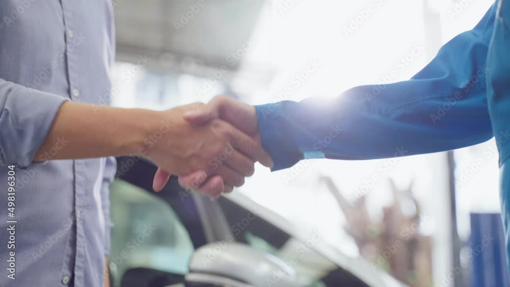 Asian automotive mechanic repairman handing car remote key to client. 