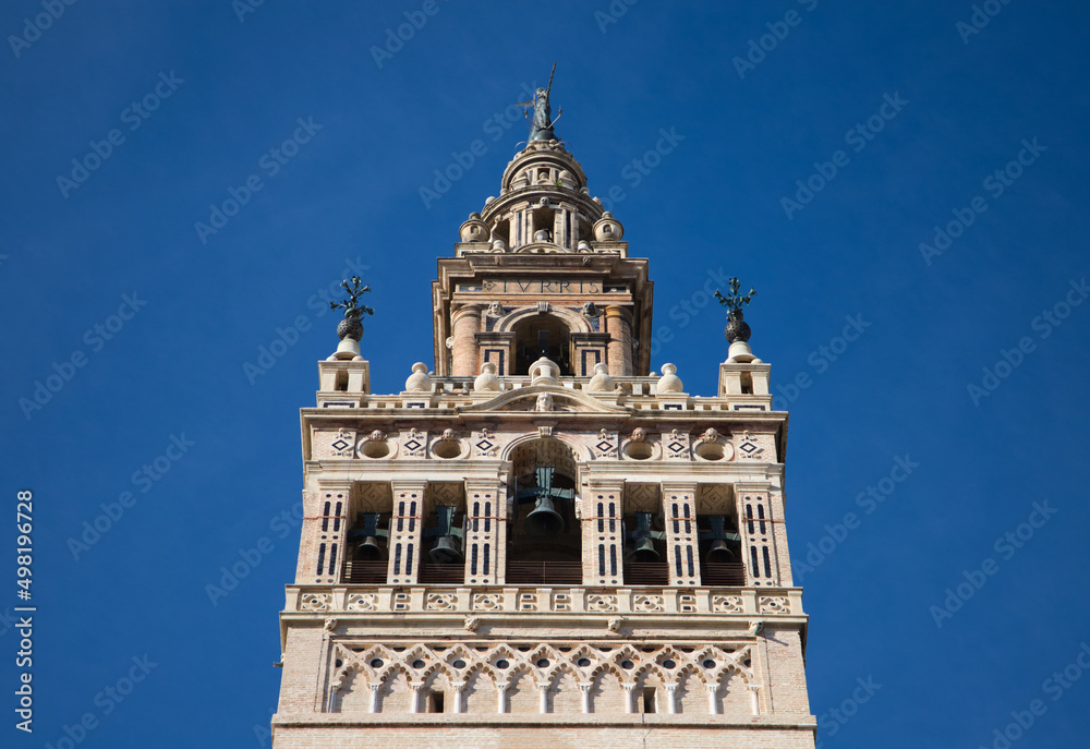 Monument of the giralda of seville in the gothic cathedral. It can be seen rising into the blue sky of the city. It is the largest religious building in the world. Tourism and travel concept.