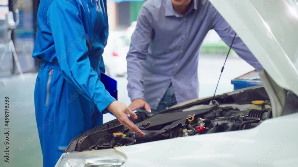 Asian automotive mechanic explain car condition to client in garage. Asian automotive mechanic explain car condition to client in garage.