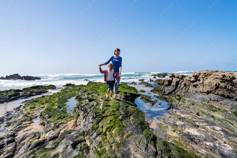 Mother and daughter walking on rocky beach Mother and daughter walking on rocky beach