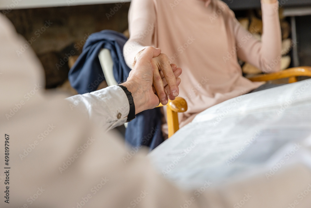Man holding woman hand sitting on chair at home Man holding woman hand sitting on chair at home