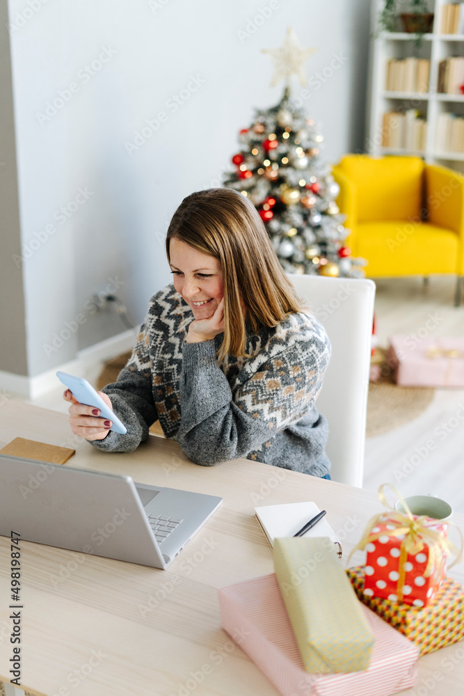 Happy woman with hand on chin using mobile phone at home Happy woman with hand on chin using mobile phone at home