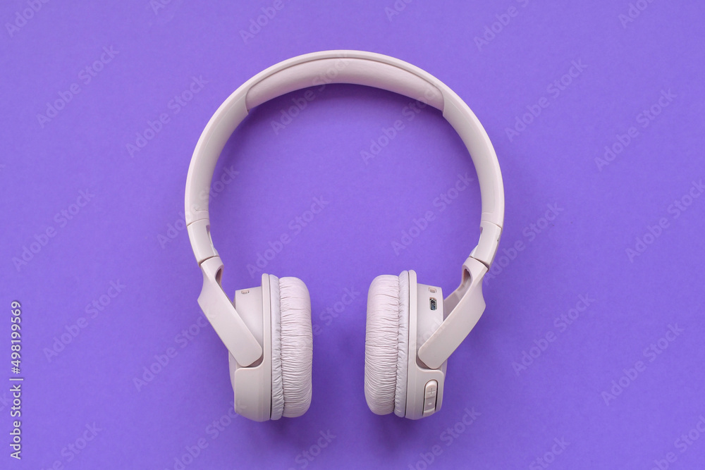 Light pink wireless headphones on brown background. Copy space.