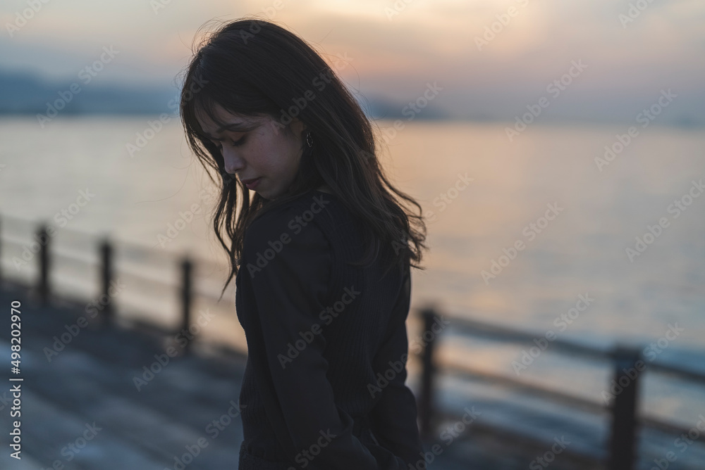 夕暮れの海沿いで散策する女性