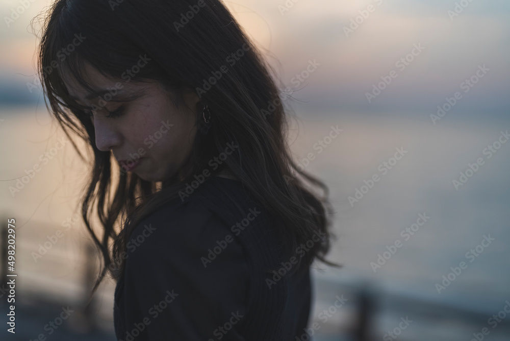 夕暮れの海沿いで散策する女性 夕暮れの海沿いで散策する女性