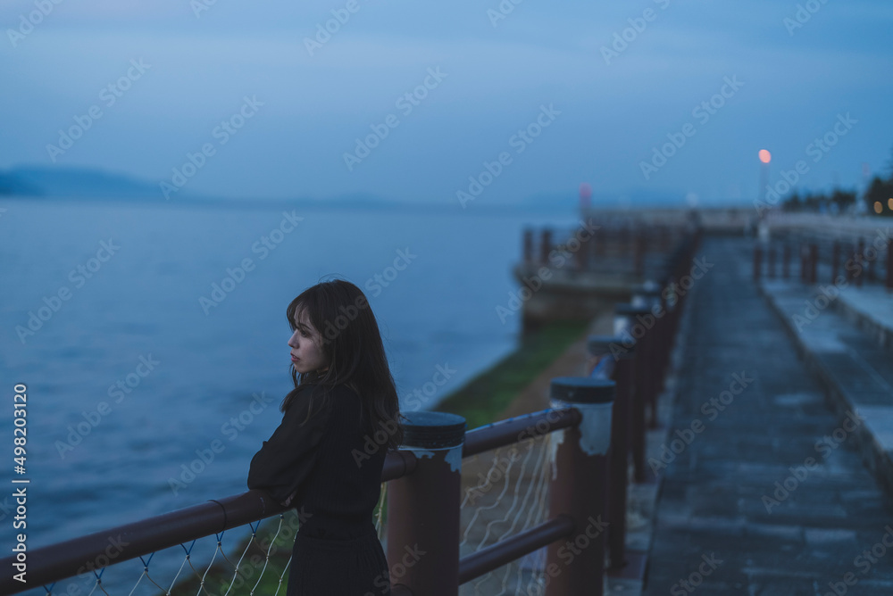 夕暮れの海沿いで散策する女性