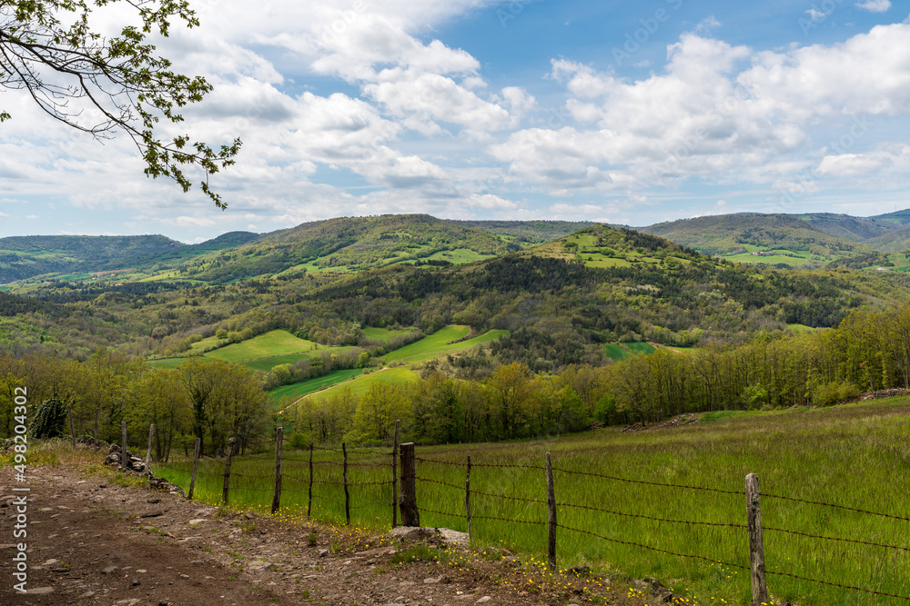 Panorama sur une vallée verdoyante avec ses belles collines boisées au printemps sur le chemin de randonnée de Boudes Chalus dans le puy de dôme