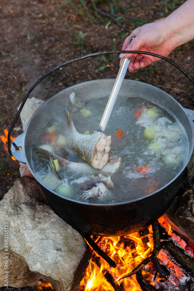 Fish soup prepared over an open fire. Cooking fish soup over an open fire in a kettle. Cooking in hiking tourism and fishing Fish soup prepared over an open fire. Cooking fish soup over an open fire in a kettle. Cooking in hiking tourism and fishing