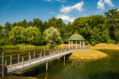 Small island in the center of park pond with round gazebo and pedestrian bridge. Feofaniya public park, Kyiv, Ukraine