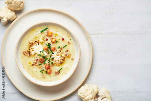 Vegan cauliflower soup on white background. Healthy vegan cauliflower soup served in bowl on white table.