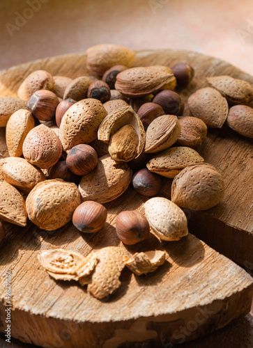 Pile of raw almonds and hazel nuts on a wooden background. Raw organic hazel nuts almonds on a wooden circle cut.