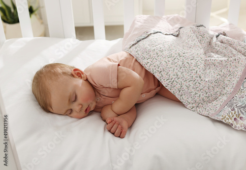 Cute little baby sleeping in soft crib at home