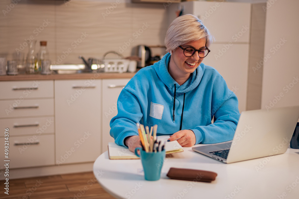 Woman working on a laptop in the kitchen at home Woman working on a laptop in the kitchen at home