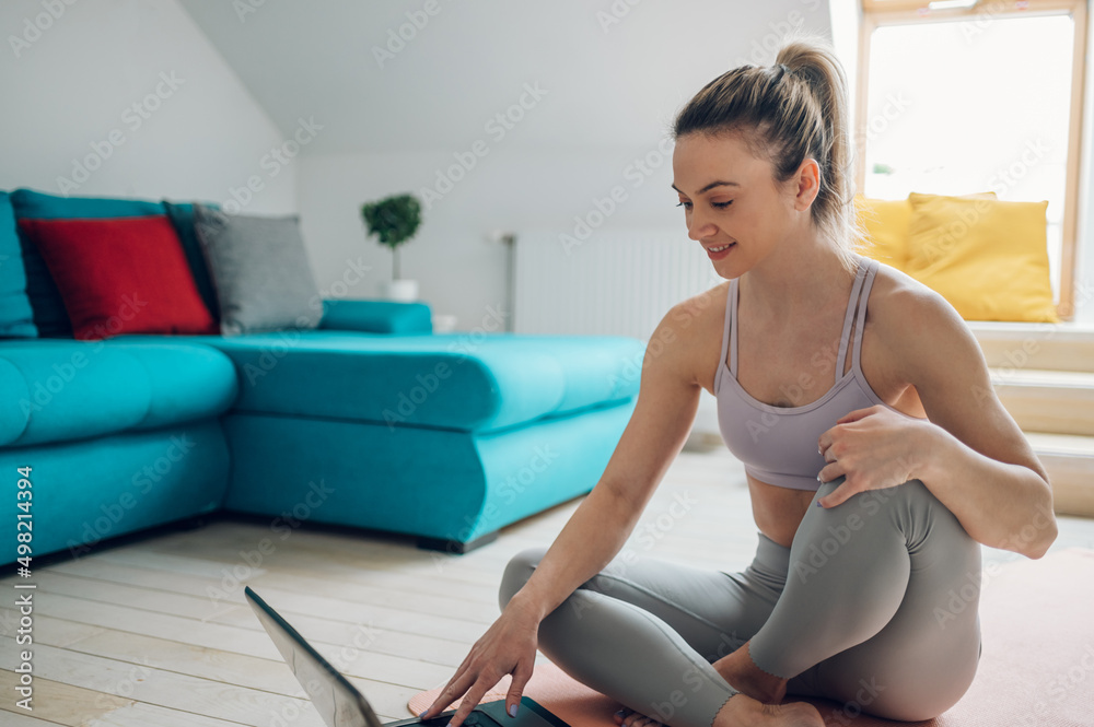 Woman training at home while using a laptop Woman training at home while using a laptop