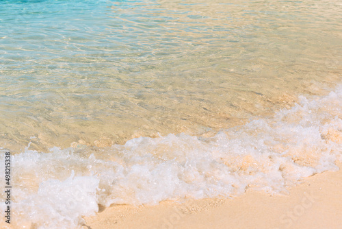 Summer scene with blue sea water and yellow sand close up with selective focus. Vacation or holiday concept. Nature background with copy space