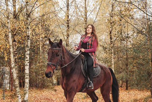 Cute young woman on horseback in autumn forest