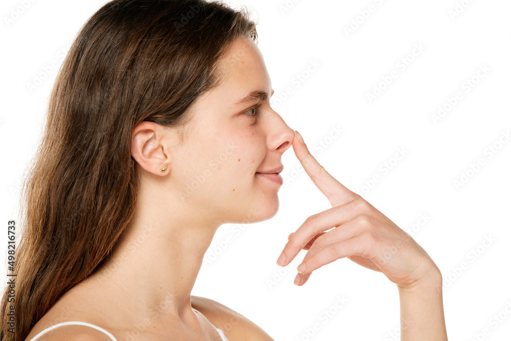 Young smiling woman touches her nose with her finger on a white background Young smiling woman touches her nose with her finger on a white background