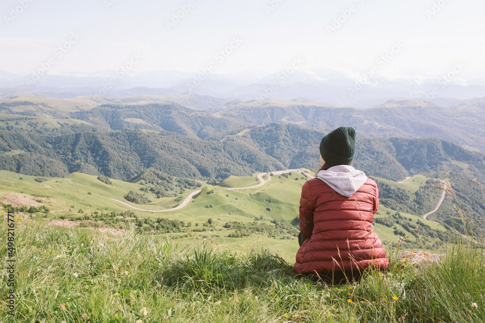 woman is sitting against background of mountains . travel, hiking, journey, outdoor recreation