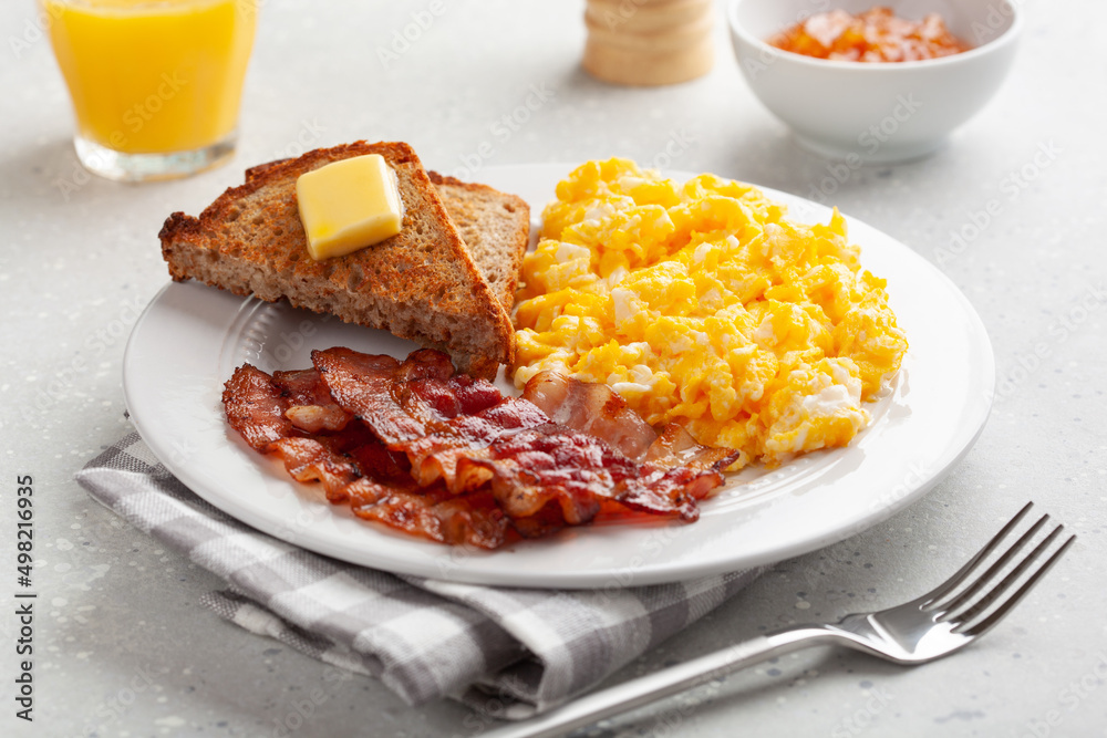 traditional scrambled egg breakfast with bacon and toast