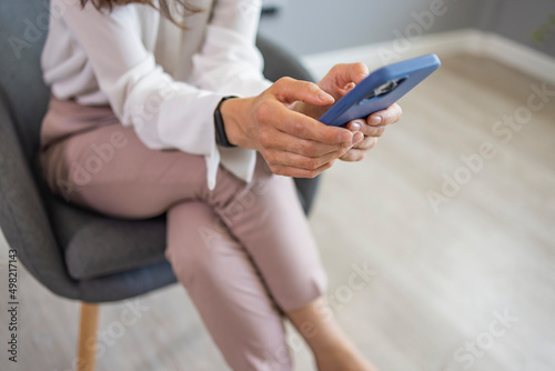Businesswoman with mobile phone in hand. Asian business woman texting on her cell phone at the office and looking happy - communications concepts
