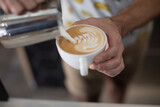 Barista pouring milk into a mug of coffee