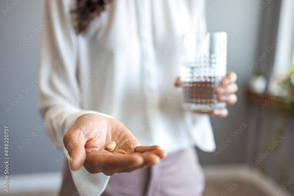 Close up woman holding pill in hand with water. Female going to take tablet from headache, painkiller, medication drinking clear water from glass. Healthcare, medicine, treatment, therapy concept Close up woman holding pill in hand with water. Female going to take tablet from headache, painkiller, medication drinking clear water from glass. Healthcare, medicine, treatment, therapy concept