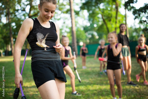 Fototapeta Naklejka Na Ścianę i Meble -  Girl surprised by sparrow landing on her during rhythmic gymnastics training in summer