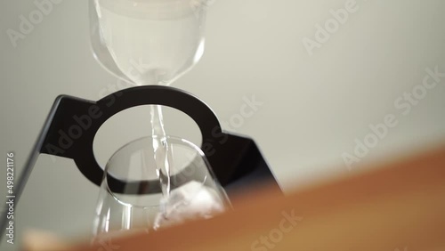 hand of barista pouring water into glass with ice cube, worm eye view