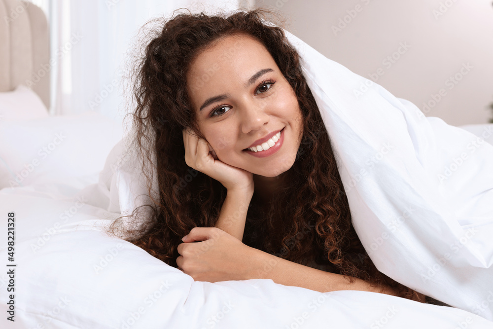 Happy African American woman lying on bed at home Happy African American woman lying on bed at home