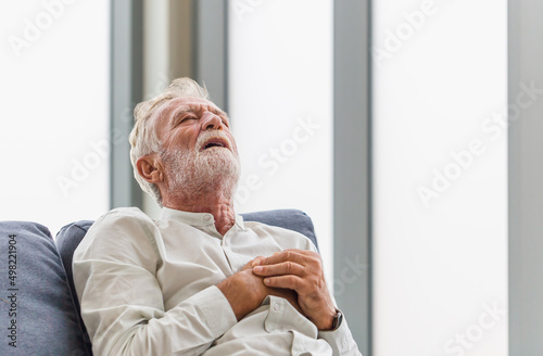 Mature man presses hand to chest has heart attack suffers from unbearable pain, Senior man with pain on heart in living room