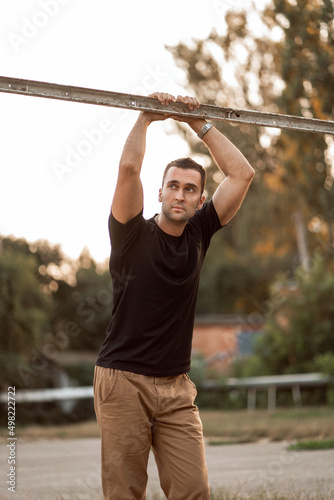 Portrait of a smiling young male athlete leaning on horizontal bars