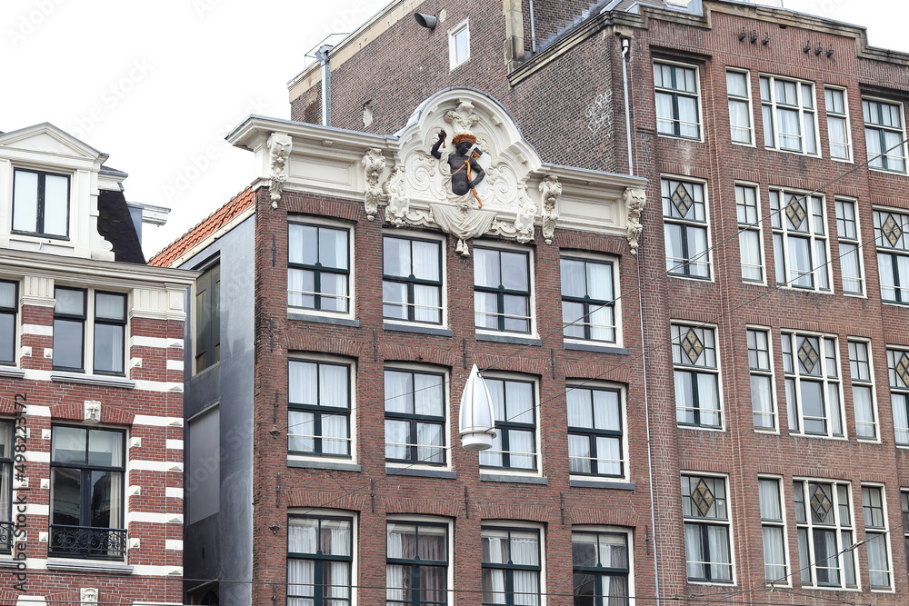 Fototapeta premium Amsterdam Rokin Street Historic Brick Building Facades with Stone Tablet Depicting a Black Man Wearing a Quiver and Holding a Bow and an Arrow, Netherlands
