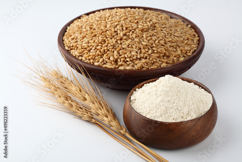Wheat flour Bunch of wheat ears, dried grains in wooden bowl, flour in wooden bowl on white background. Cereals harvesting, bakery products