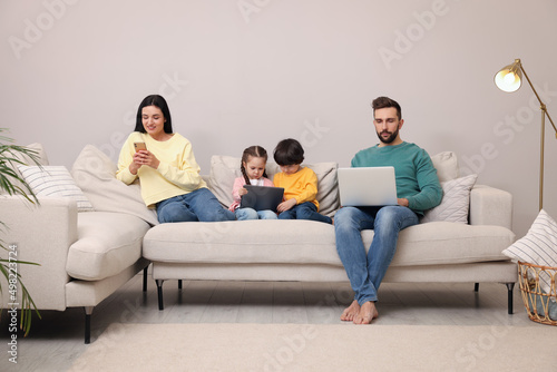 Happy family with gadgets on sofa in living room