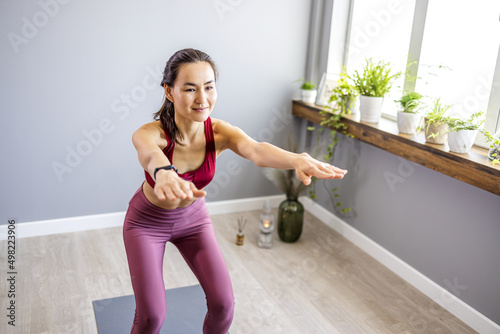 A Asian attractive woman practices yoga, stretches in an exercise, exercises, wears sportswear, an upper and trousers, in full length, studio background. The concept of yoga and training photo