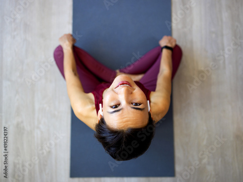 Attractive Asian woman practices the concept of yoga, sits in an exercise on a yoga mat, Balasana pose, exercises, wears sportswear, sleeveless T-shirt and pants, full length, white attic background. photo